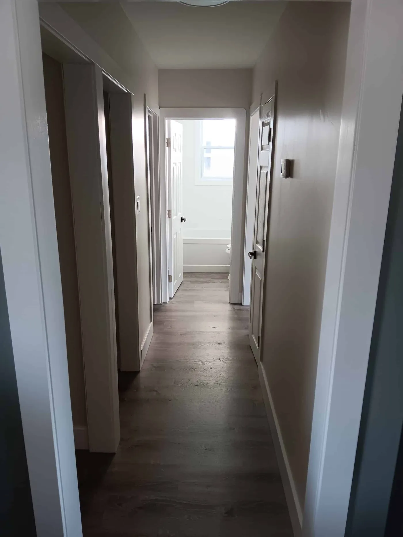 Freshly painted hallway with white doors and trim leading to a bright room